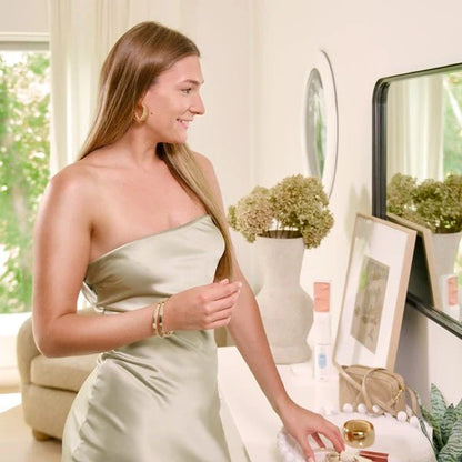 Woman in a light green dress standing in a room with decor elements.